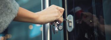 business owner using a key to open front door